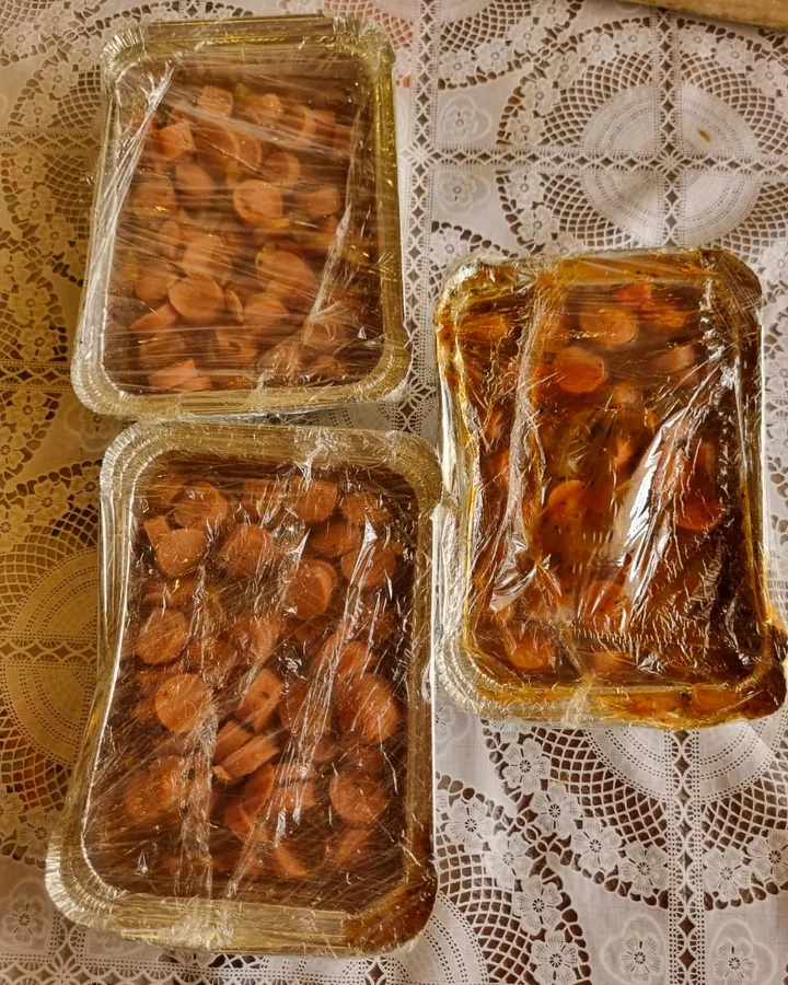 Bandejas de aluminio con salchichas en salsa, tapadas con film para el evento