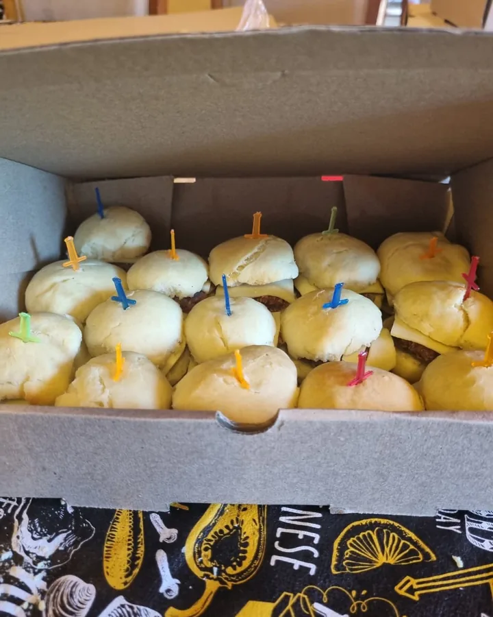 Caja con mini hamburguesas en pancito casero con palillos de colores